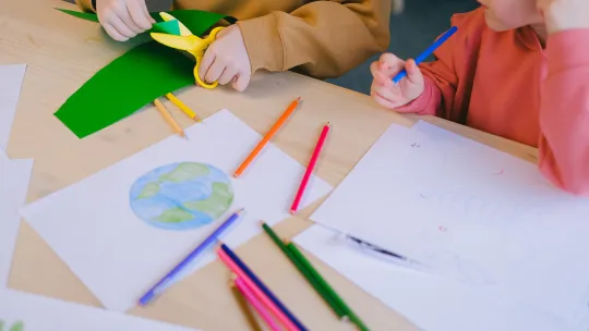 Drawing of Earth and children cutting paper with scissors