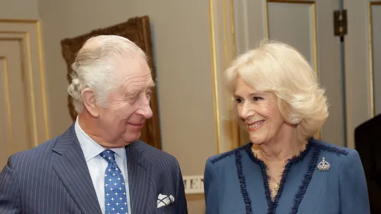 King Charles and Queen Consort Camilla smile at each other.