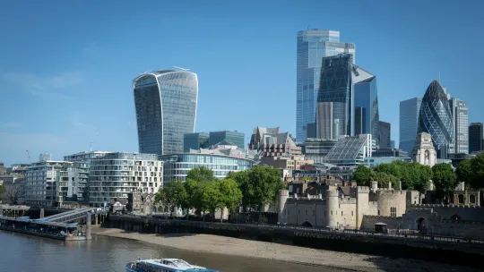 Image of London skyline with a boat in the foreground on the Thames river