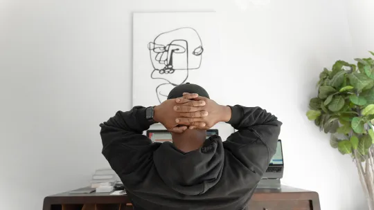 a man sitting at a desk with his hands behind his head