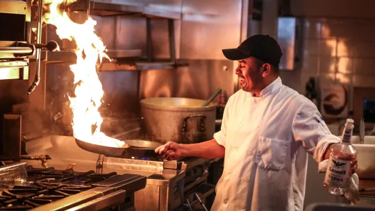 a restaurant chef using a frying pan in a kitchen