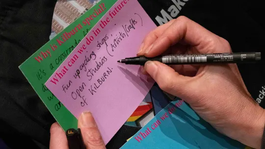 Close up of someone writing on their thoughts at a public engagement event