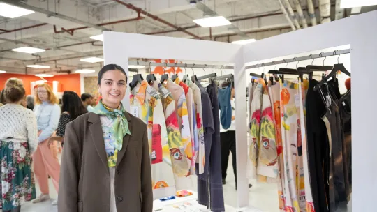 Woman with presentation table and rail of clothes