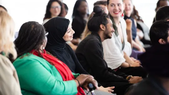 A photo of people from diverse backgrounds, talking and laughing at an event