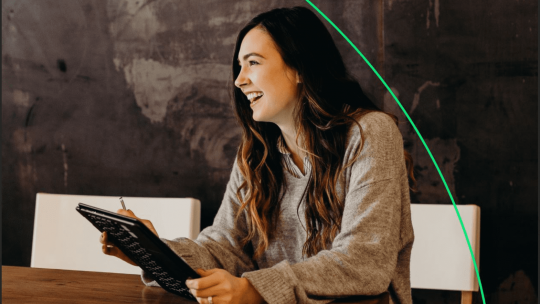 Woman in the office, smiling and holding a laptop