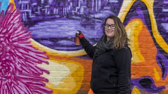 Artist standing in front of painted mural, part of the where are the women project