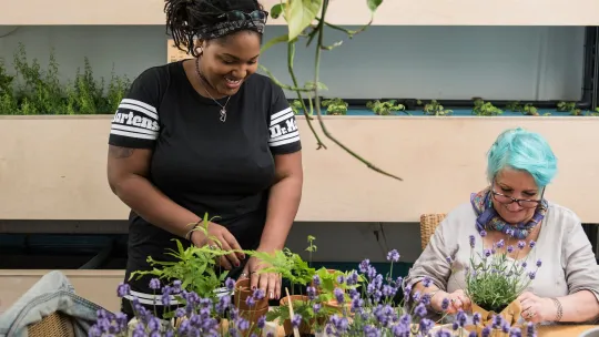 Photo showing two volunteers working in a plant shop in Dalston