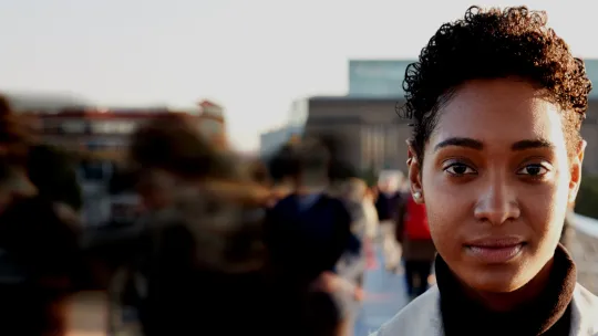 Image of woman in foreground with blur of people walking in background