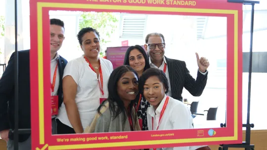 6 people smiling at the camera with a pink selfie board outlining the group