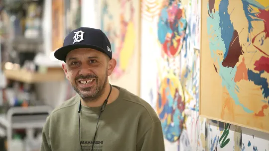 Artist in studio with artwork in the background