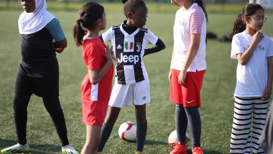 Group of five girls get ready to play on a football pitch