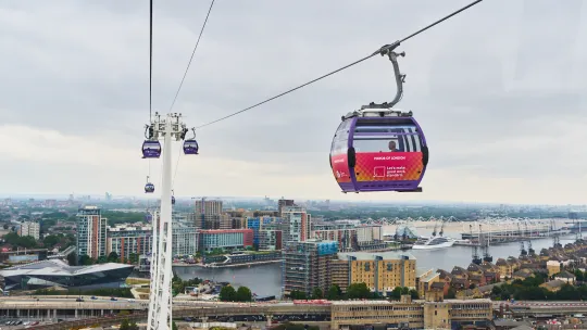 Cable car above London skyline with a pink branded cabin visible