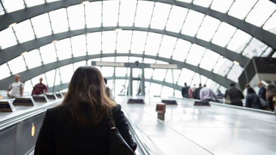 Woman travelling up escalator in Canary Wharf tube station
