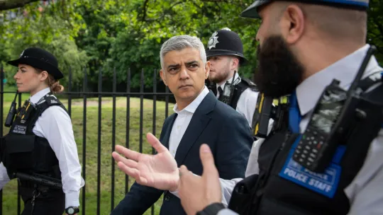 Mayor of London, Sadiq Khan, talking to a police officer as they walk past a park