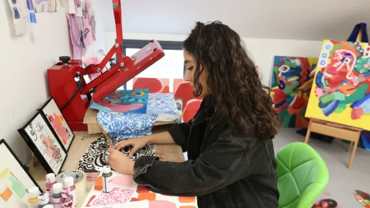 Woman sitting at a desk working with textiles and prints