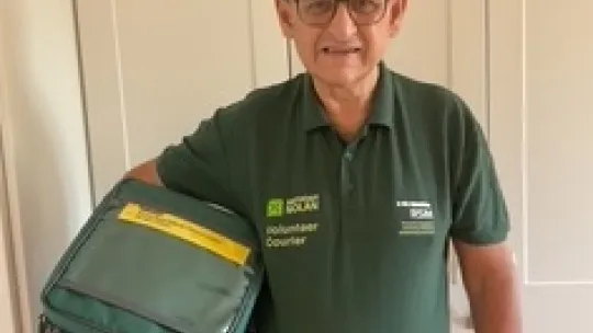 Volunteer in green uniform holding chiller bag