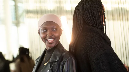 Two smiling young women standing back to back