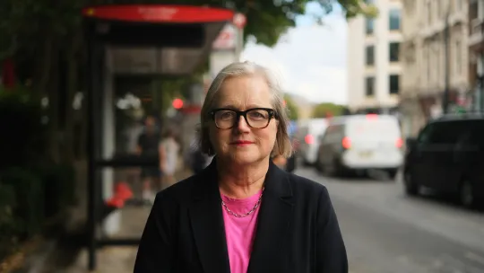 Caroline Russell AM standing in front of a bus stop