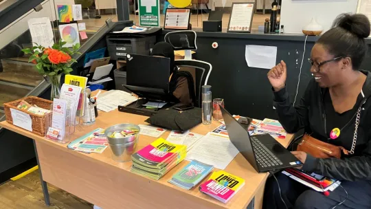 Oasis Waterloo Summer Wrap-Up Party reception desk - employee sitting at the reception desk with Loved and Wanted leaflets displayed on the desk