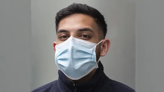 A headshot of a NHS staff member wearing a facemask.