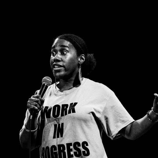 Monochrome image of a live performer on stage holding a microphone