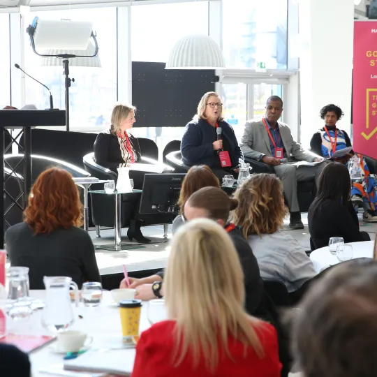 People on a stage on a panel with audience members