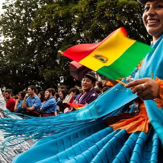 Women dancing wearing a blue dress and holding a flag