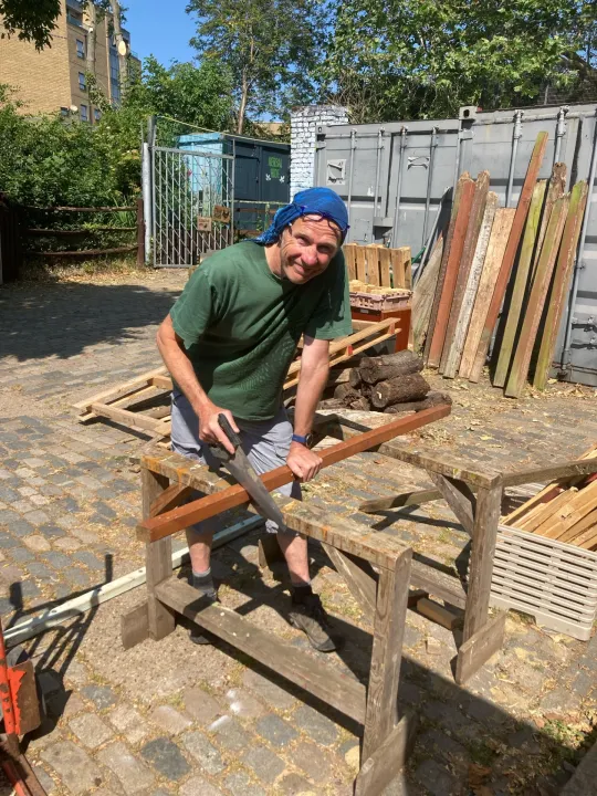 Volunteer Neil sawing a piece of wood at Spitalfields City Farm