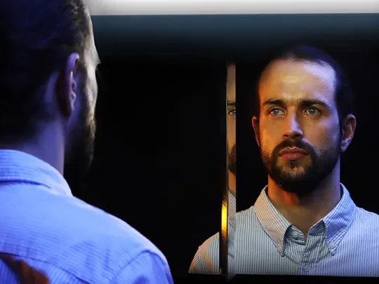 A white male looking into a mirror.