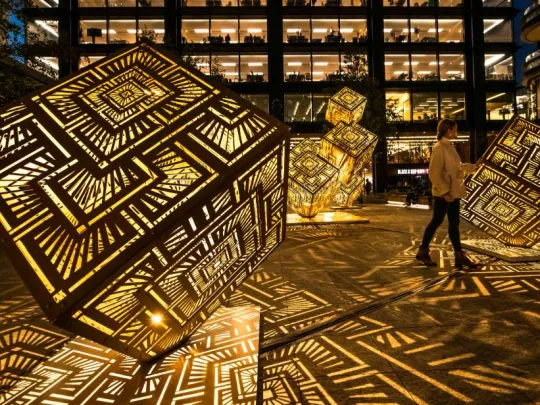 John Nguyen Wire Principal Place Cube with lights showcase with a person lookin