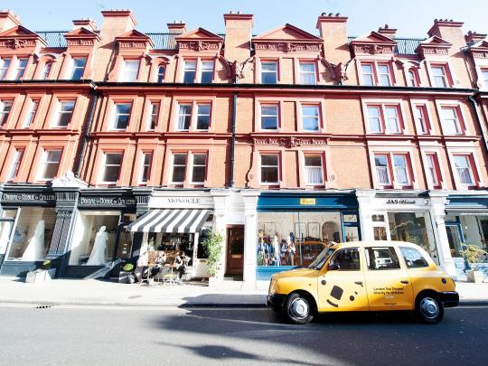 Yellow taxi parked on the street front of shops