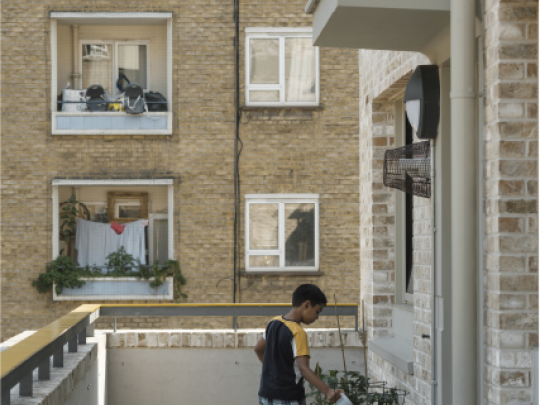 A boy waters plants on a balcony