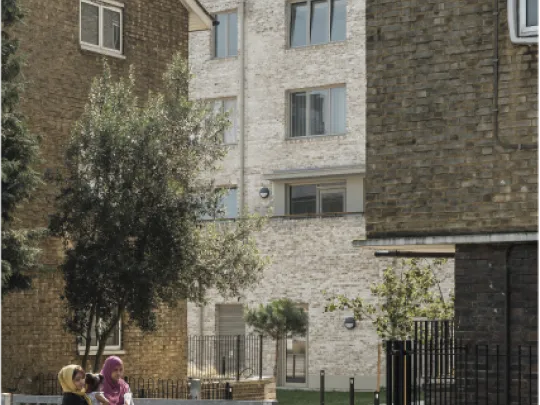 Two women walking past a tree lined courtyard