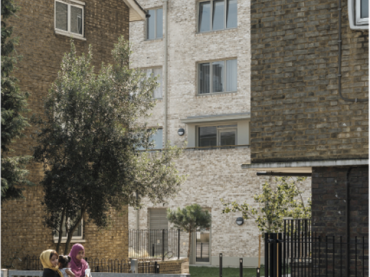 Two women walking past a tree lined courtyard