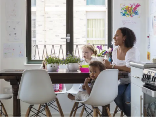 A woman and two children eating in a bright kitchen