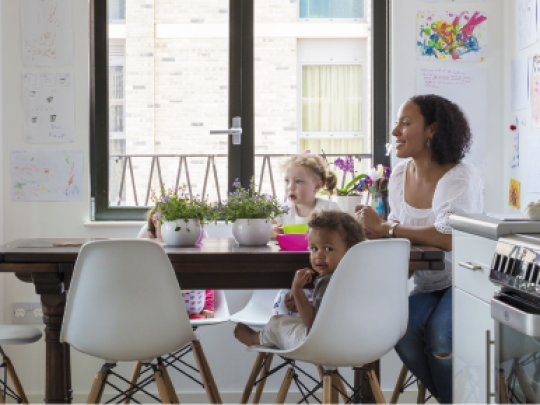 A woman and two children eating in a bright kitchen