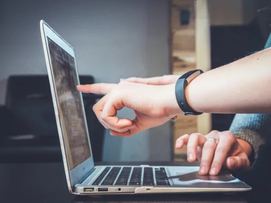 People pointing at laptop screen