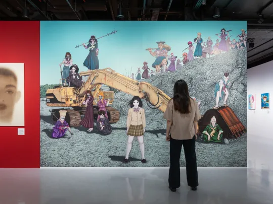 Woman stands in front of a large mosaic painting on the wall