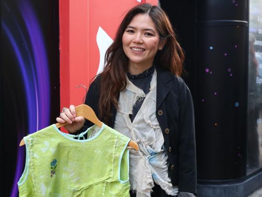 Person standing outside holding clothing