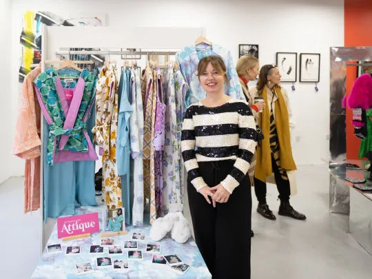 Woman in a shop with clothes rails. 