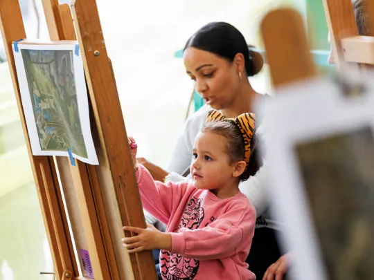 Mother and daughter drawing on an easel