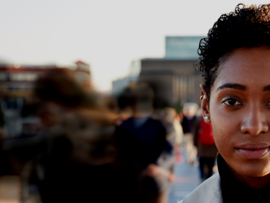 Image of woman in foreground with blur of people walking in background