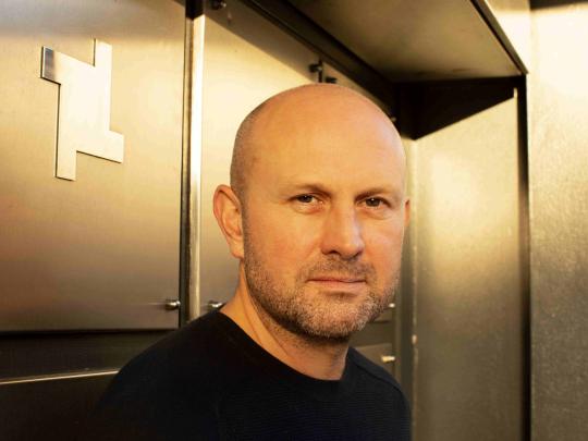 Man looking at camera with silver wall in background.