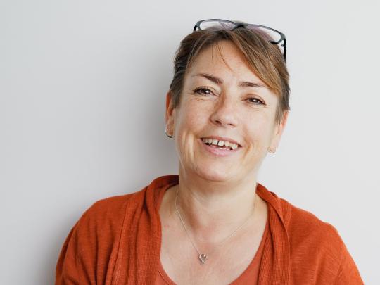Woman smiling with glasses on their head looking at the camera.
