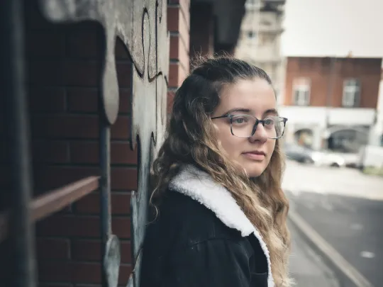 Young woman leaning against a wall