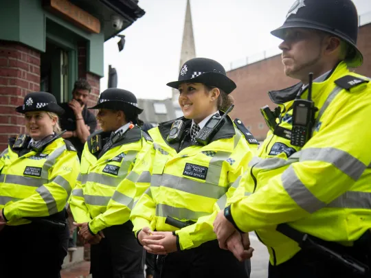 Group of female and male police officers looking relaxed and smiling as they stand to attention outdoors