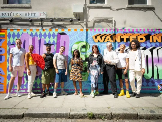 People standing in front of Loved and Wanted pride mural