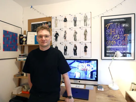 person standing in in their digital studio with art on the walls
