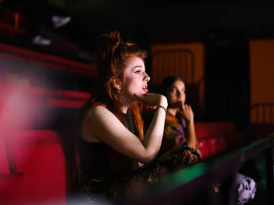 Young woman sitting in theatre seats at rehearsal