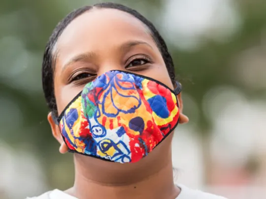 Young person wearing bright face covering
